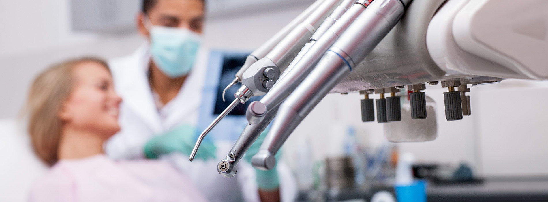 The image shows a modern dental clinic interior with various pieces of equipment, including a dental chair and an X-ray machine.