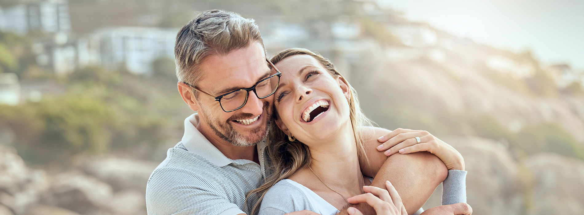 A person is seated in a dental chair, receiving care from a dental professional who stands behind them.