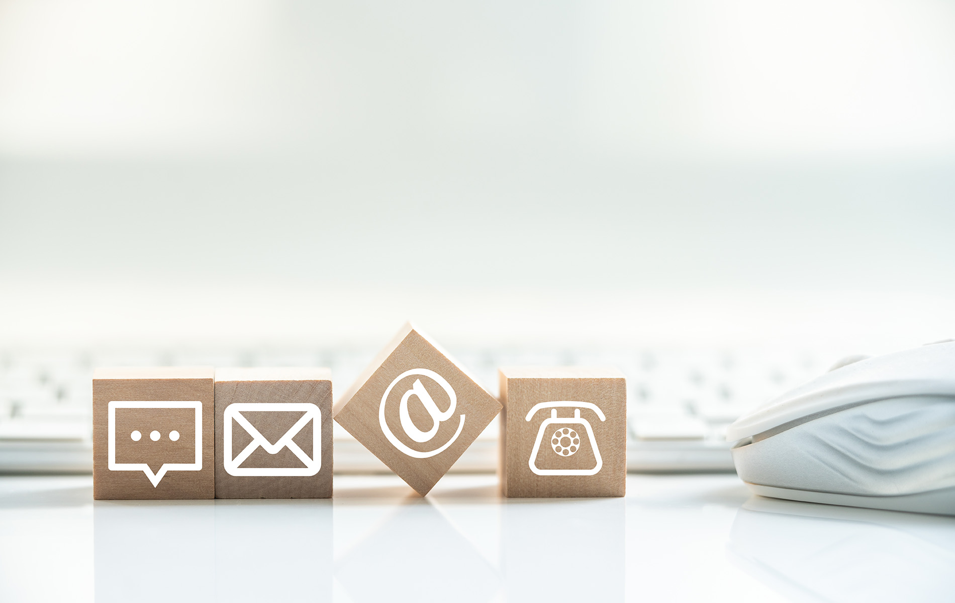 The image shows a collection of block-shaped objects resembling computer icons, such as Wi-Fi, battery life, and volume control, arranged on a surface with a blurred background that suggests a workspace environment with a keyboard and mouse.