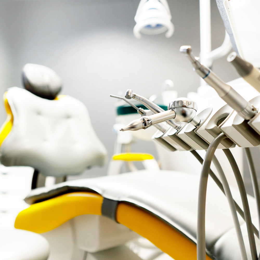 The image shows a dental office interior with a dental chair, a dental light, and various dental equipment.