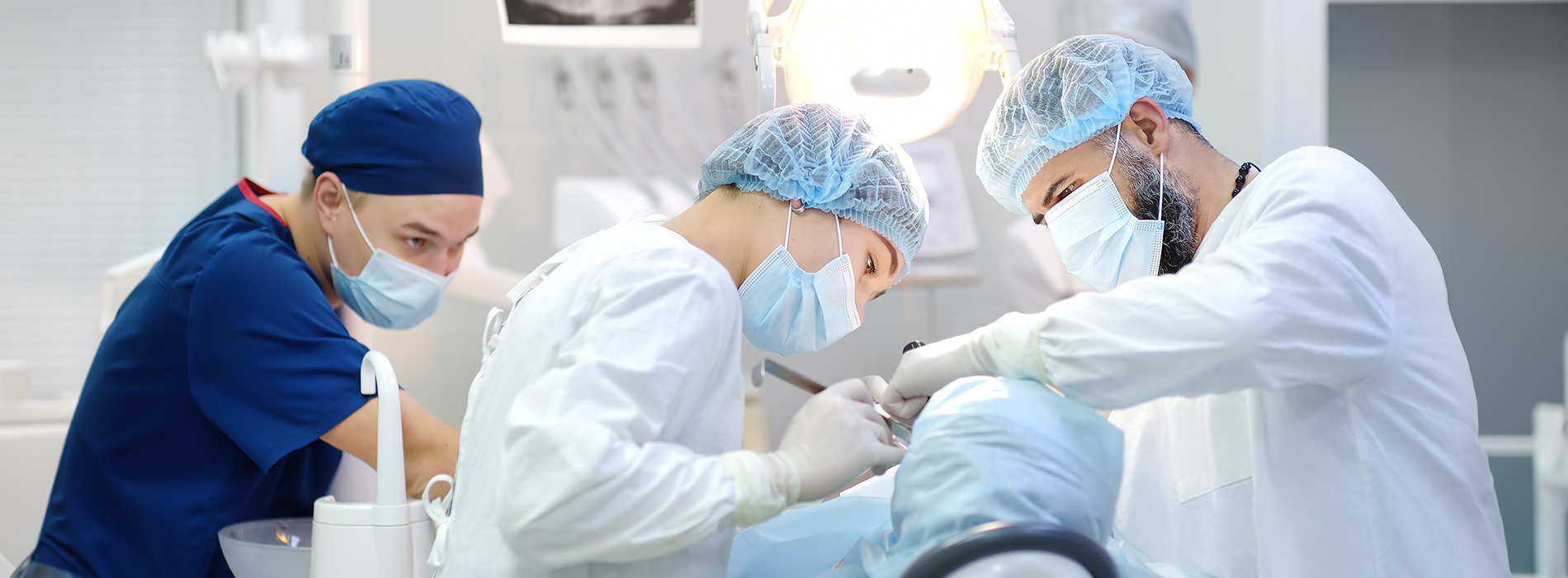 Image depicts a group of medical professionals performing surgery in an operating room, with a focus on a surgeon at the center surrounded by other staff members.