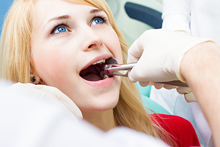 A woman with blonde hair receiving dental treatment from a professional in a medical setting.