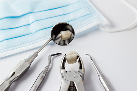 The image shows a collection of dental tools including a toothbrush, toothpaste, and dental picks arranged on a white background with blue surgical drapes, suggesting a dental care setting.